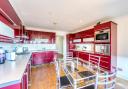 The kitchen is fitted with a comprehensive range of sleek red units