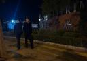 Plainclothed police pass by the Beijing primary school following the attack (Andy Wong/AP)