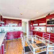 The kitchen is fitted with a comprehensive range of sleek red units