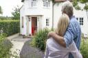 Rear View Of Mature Couple Standing In Garden Look At Dream Home In Countryside